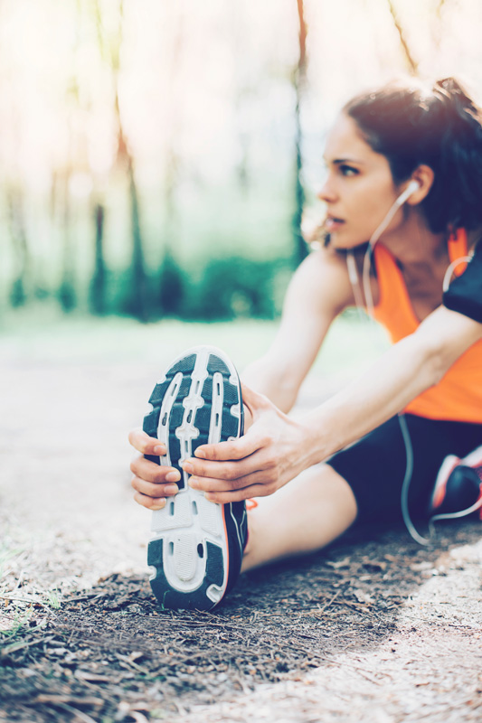 Athlete stretching leg and running shoe outdoors prior to a training session