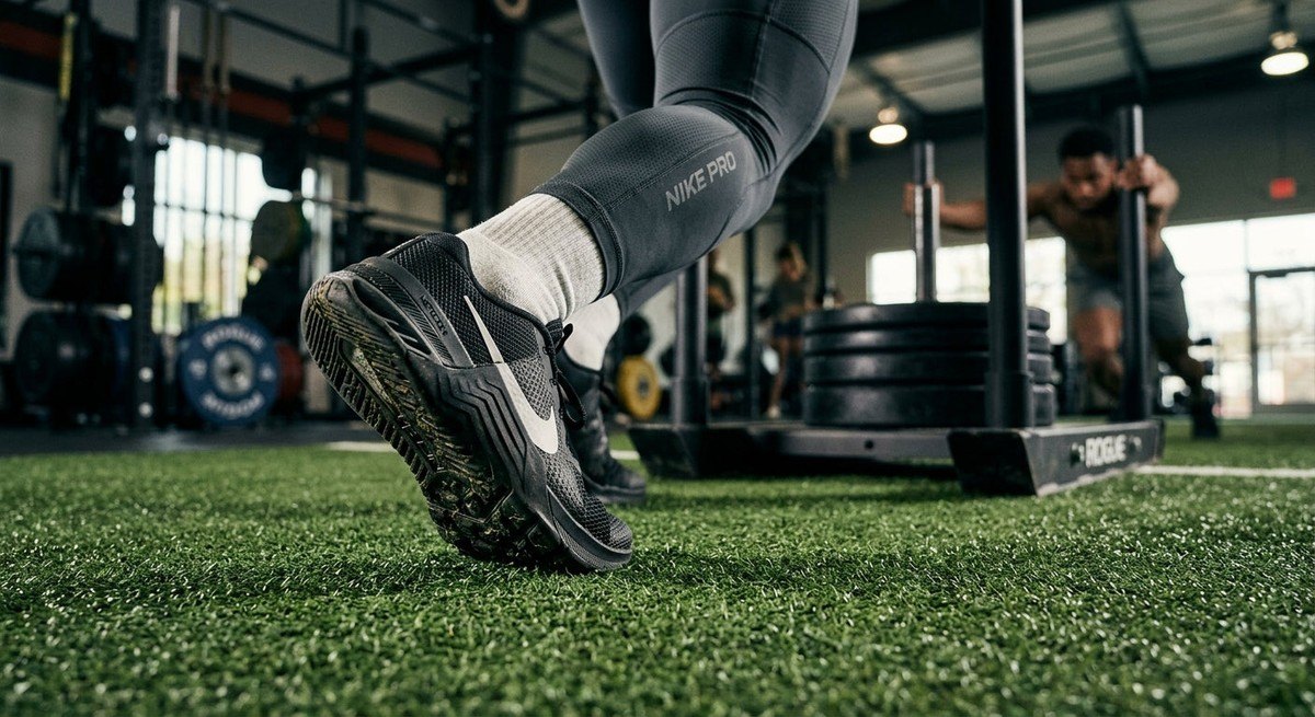 Athletic shoe outsole gripping indoor turf during an intensive weighted sled push workout.